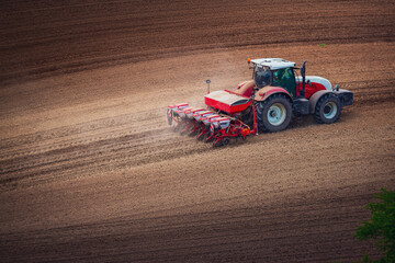 Farmer in tractor preparing farmland with seedbed for the next year, tractor seeding crops at field...