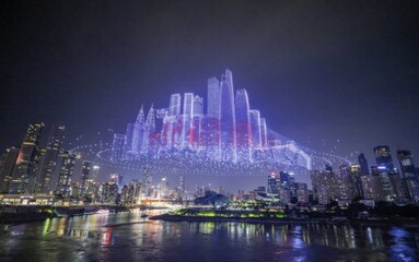 Illuminated drone skyline show above modern city at night with reflection on water below