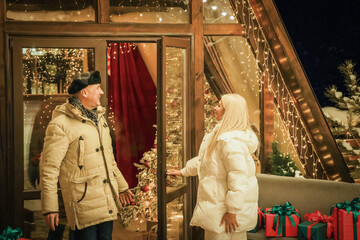 Couple enjoys festive shopping for Christmas gifts while surrounded by holiday decorations. Festive...