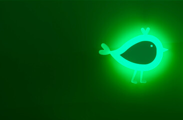 A stylized Plexiglas, light-green-glowing bird silhouette is affixed to a deep crimson-red wall