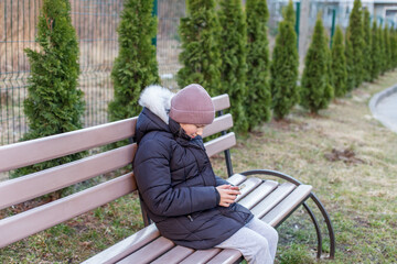 Kid using phone alone on park bench