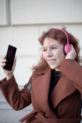 Naklejka premium Young woman enjoying music with pink headphones