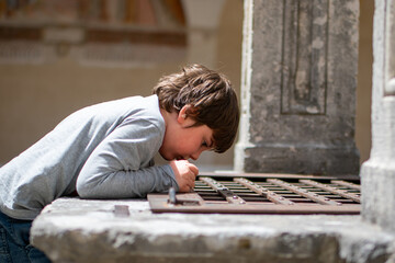 Curious young boy exploring monastery architecture during a tour in Italy