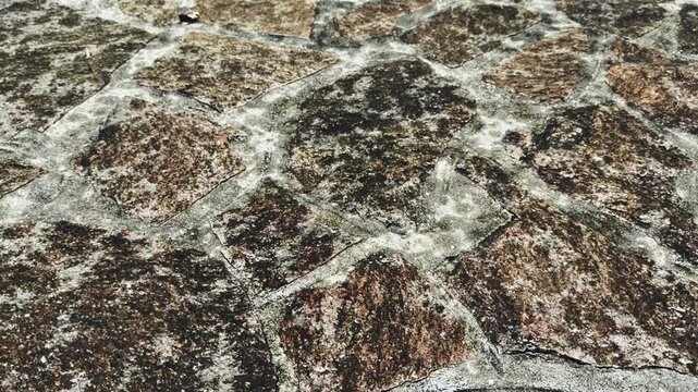 gocce di pioggia cadono su una superfice pavimenttata in pietra, vista ravvicinata liveelo terreno con zoom in