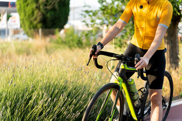 Professional cyclist holding handlebars of gravel bike near lavender field