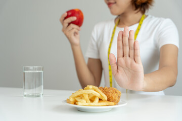 Beauty slim female body confuse French fries and fried chicken. Woman in restaurant achieves weight...