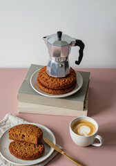 Italian moka pot on freshly baked carrot cakes with latte on pink table