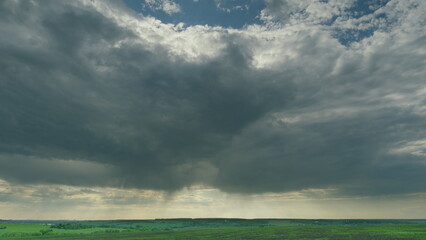 A Moody Cloudscape Draped Over an Expansive and Lush Green Field Beneath the Sky Time lapse.