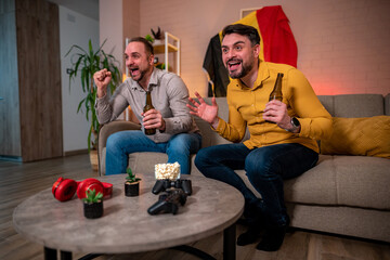 Friends celebrate and cheer while watching a game at home together