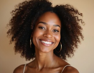 Happy African american woman with healthy skin smiles at camera. Beautiful black female with natural beauty. Joyful lady with white teeth, curly hair. Authentic expression.