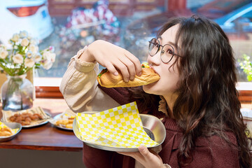 Oriental women eating a lot at the Meiyan hot dog fast food restaurant