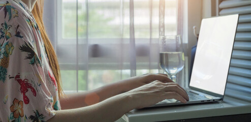 working from home, remote work concept. side view of Asian woman wearing casual shirt using laptop...