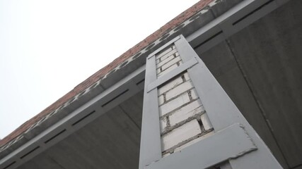 Brick column reinforced with metal bars supports massive porch. Structural strength visible in firm junction. Combination ensures stability