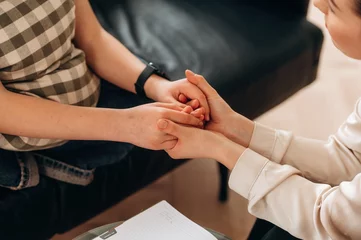 Fotobehang Support conception. Close up view of woman psychologist that is supporting young girl by holding her hands © standret