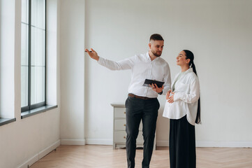 Realtor is showing the interior. Man and woman are in the modern new room, conception of business
