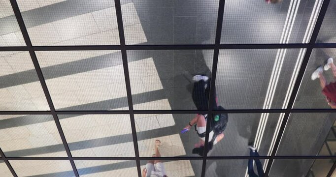 Unrecognizable city commuters walking reflected in a ceiling mirror. Underground railway station in a European city, inverted perspective, real time