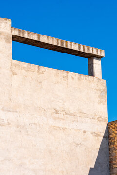 Modern white concrete wall with architectural cutout under clear blue sky, highlighting minimal design, clean geometry, and abstract urban composition in contemporary city architecture