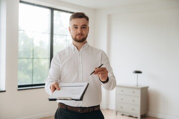 Pen in hand, sign the deal, buy new home. Real estate agent is in the new room
