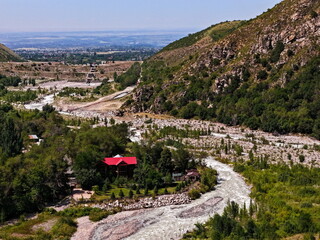 The bank of a mountain river with a house on the outskirts. Talgar gorge. Mountainous area with different vegetation.