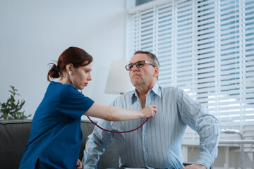 Doctor with stethoscope examining elderly patient with examination, presenting symptoms and...