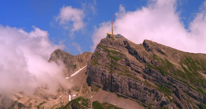 Stunning view of mountain summit with observatory surrounded by clouds in bright blue sky