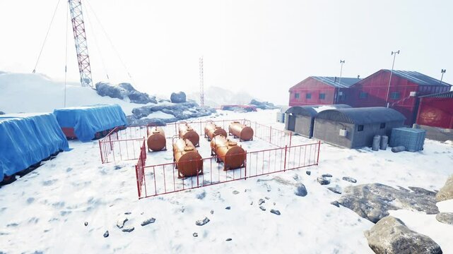 The research station in Antarctica features red buildings and storage tanks, surrounded by snow-covered terrain, where scientists conduct important weather experiments.