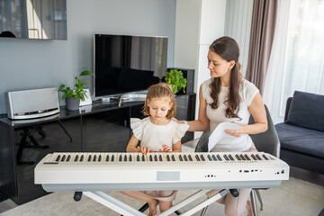 Individual piano lesson for a young child at home in the living room. Concept of early childhood...