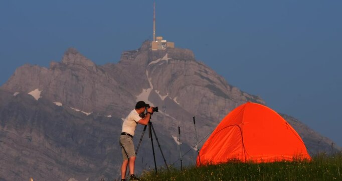 Landscape photography in the mountains with vibrant orange tent at sunset