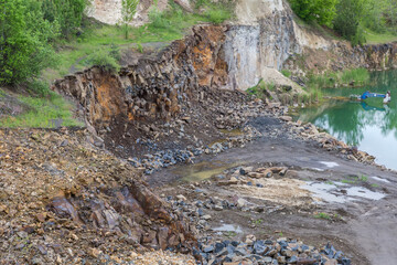 Side of partially flooded basalt quarry in overcast rainy day