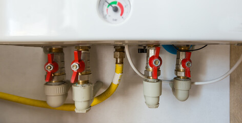 Water fittings on wall-mounted household gas boiler close-up