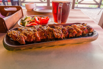 Baked pork ribs under honey mustard sauce on wooden tray