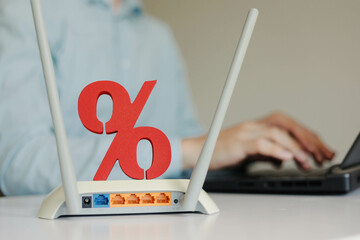 Wireless high speed wifi router with sign of percent on the table. Man using laptop on the...