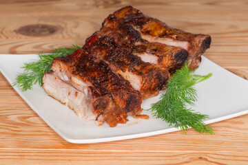 Sliced baked pork ribs portion on plate on rustic table