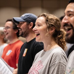 "Members of a chorus smile and sing during a rehearsal session.