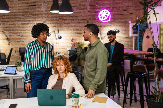 Marketing team discussing new project on laptop in modern office