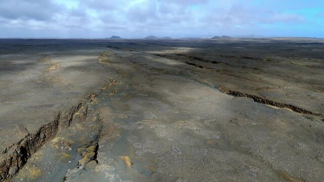 aerial view of The Bridge between Continents footbridge spanning a rift between the Eurasian and North American tectonic plates cloud shade on the arid ground