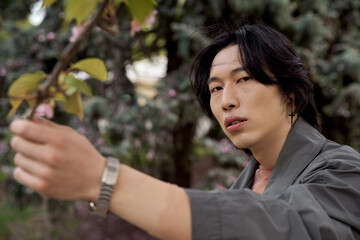 Stylish young man showcases fashion in a serene park setting during springtime