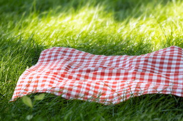 Red checkered picnic towel plaid on grass, tablecloth outdoors.Food advertisement template.