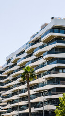 Contemporary residential apartments with wavy white balconies and glass exterior. Urban residential structure for city living and real estate marketing purposes.