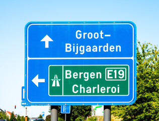 Blue and green traffic sign tot the E 19 Mons Charleroi highway in Dilbeek, Flemish Brabant, Belgium