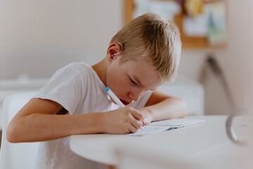 Young mother helps her hard-of-hearing son with schoolwork at home. A natural, heartfelt moment of...