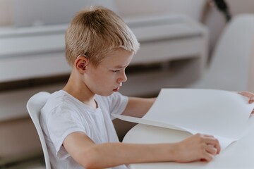 Young mother helps her hard-of-hearing son with schoolwork at home. A natural, heartfelt moment of...