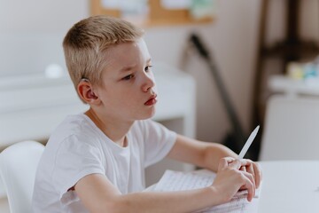 Young mother helps her hard-of-hearing son with schoolwork at home. A natural, heartfelt moment of...