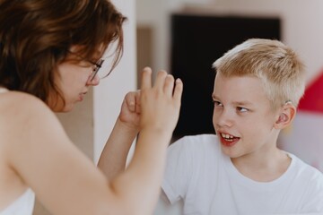 Young mother helps her hard-of-hearing son with schoolwork at home. A natural, heartfelt moment of...