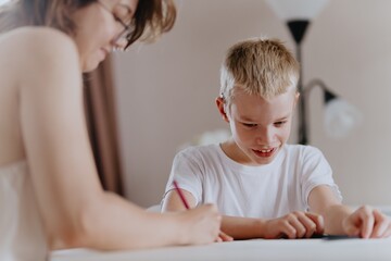 Young mother helps her hard-of-hearing son with schoolwork at home. A natural, heartfelt moment of...