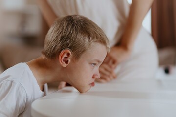 Young mother helps her hard-of-hearing son with schoolwork at home. A natural, heartfelt moment of...