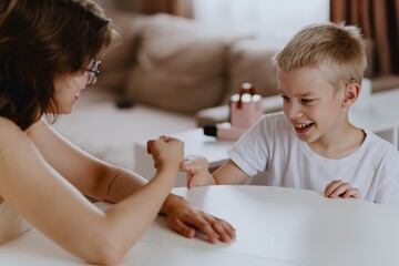 Young mother helps her hard-of-hearing son with schoolwork at home. A natural, heartfelt moment of...