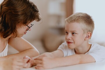 Young mother helps her hard-of-hearing son with schoolwork at home. A natural, heartfelt moment of...