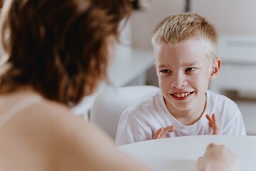 Young mother helps her hard-of-hearing son with schoolwork at home. A natural, heartfelt moment of...