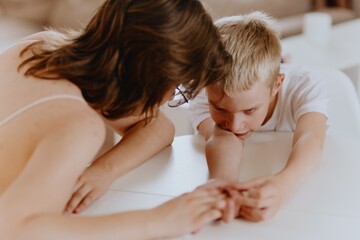 Young mother helps her hard-of-hearing son with schoolwork at home. A natural, heartfelt moment of...